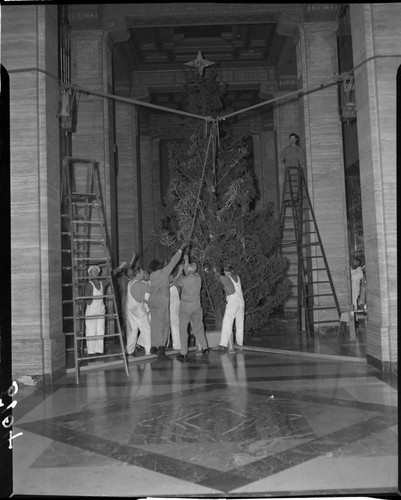 Men erecting Christmas tree in Edison General Office lobby