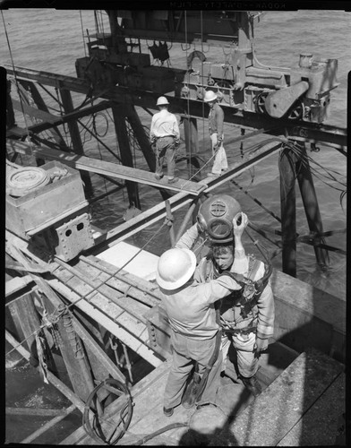 Diver in diving suit having helmet placed, and fastened at construction site