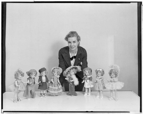 Woman posed with eight of the dolls