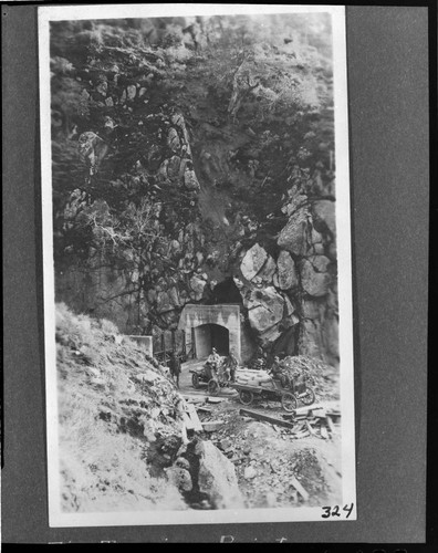Men in their automobiles near mouth of tunnel