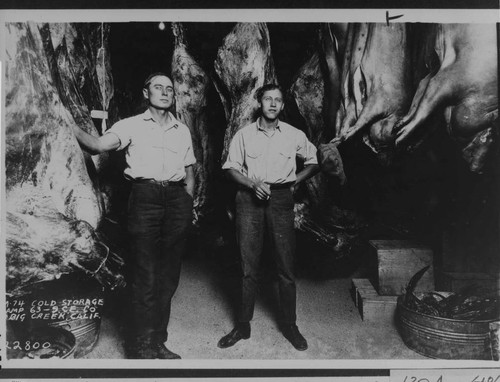 2 men in the Camp 63 refrigerator used for storage of meat and other perishables at Big Creek