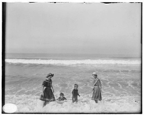 Two women and two young boys at the beach playing in the surf