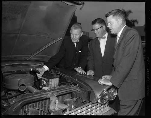 Men demonstrating the use of an early smog control device that vented engine exhaust back into air cleaner