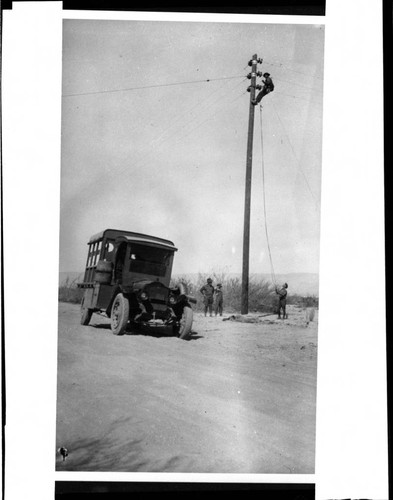 Linemen stringing conductor on pole