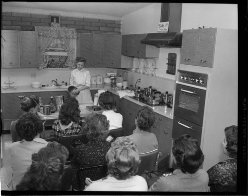 Cooking demonstration promoting electric appliances to a group of women with 9 variants