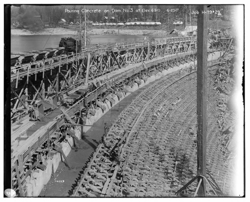 Big Creek Huntington Lake Dams - Pouring concrete on Dam #3 at elevation 6910. [Locomotive pushing concrete batch cars onto dam] Job H