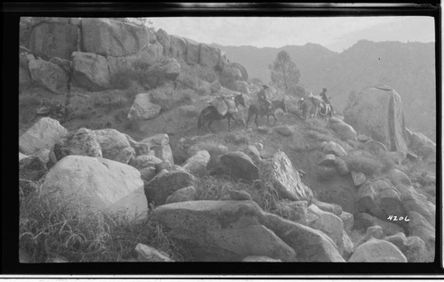 Men on horseback on mountain trail with pack horses