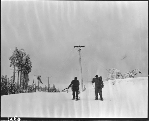 Linemen walking to distribution pole with snow shoes