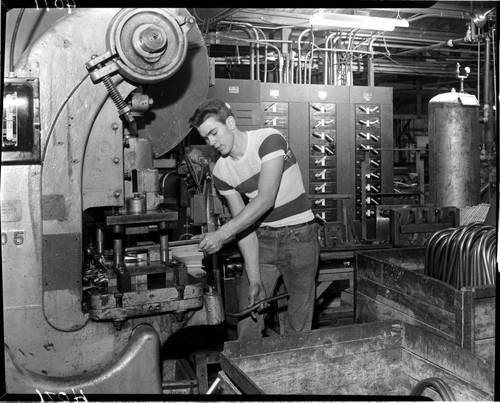 Man bending tubes at a metal brake in a machine shop