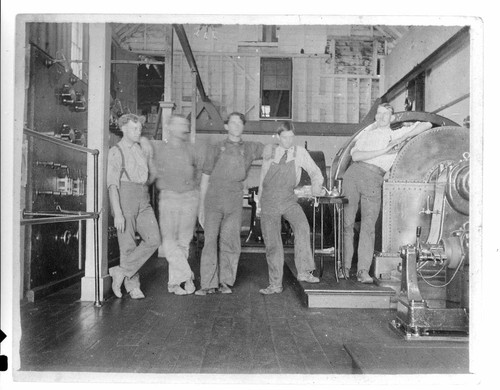 Five men standing next to the switchboard and generators in Mill Creek #1 Hydro Plant