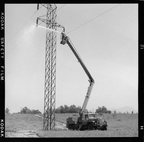 Lineman washing tower insulators from bucket with high pressure nozzle