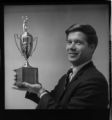 Two men in an office - one with a trophy