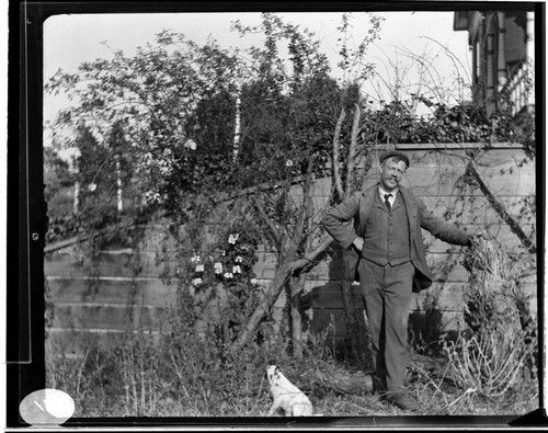 A man standing near a wall with a small dog