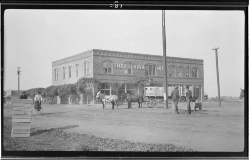 View of the Kirk Hotel in Exeter with two men standing in front of a horse buggy