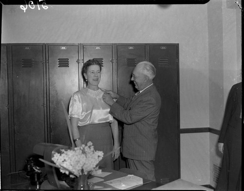 Man pinning service pin to womans blouse