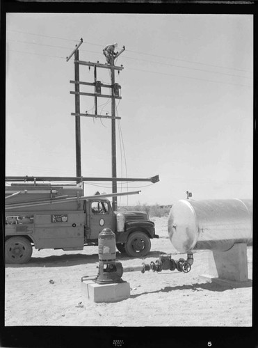Linemen installing transformers on a pair of distribution poles in the desert