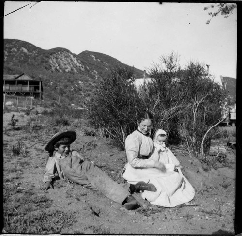 A woman with a baby on her lap and a young boy by her side