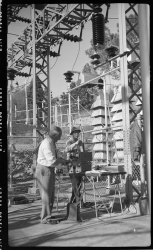 Engineers running tests in switch racks at electric substation