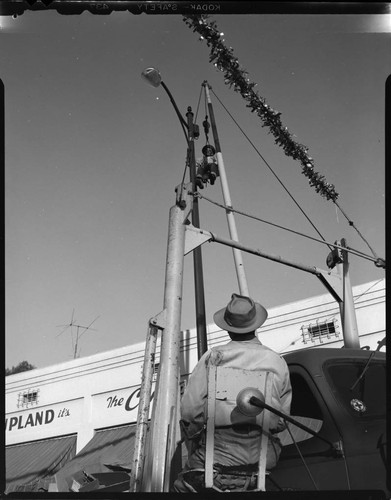 Utility workers hanging Christmas decorations on street light poles