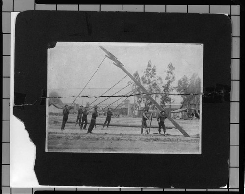 Crew of 7 men erecting distribution pole by hand