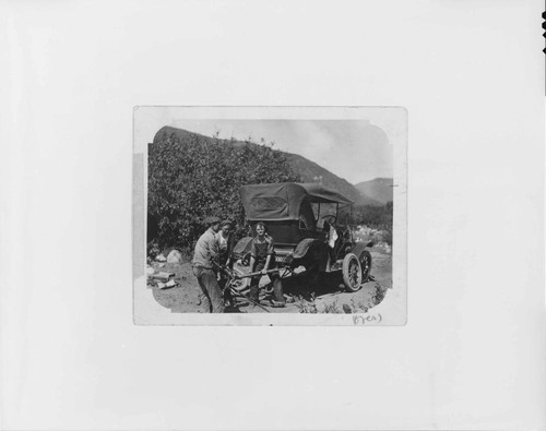 A repair crew attempting to repair a car that broke down on an inspection tour by a party of Edison officials to Kern River #1 Hydro Plant