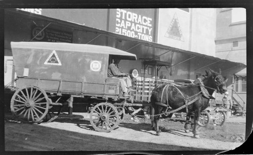 Man at reins of large horse drawn Ice wagon in front of the Imperial Ice Company