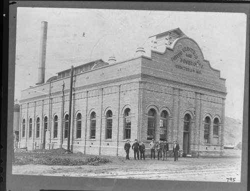 A group of men standing in front of the Santa Barbara Steam Plant