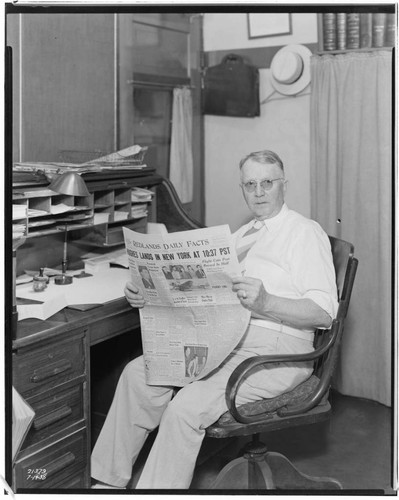 Man at the newspaper reading a (hot off the press) copy of the "Redlands Daily Facts" newspaper