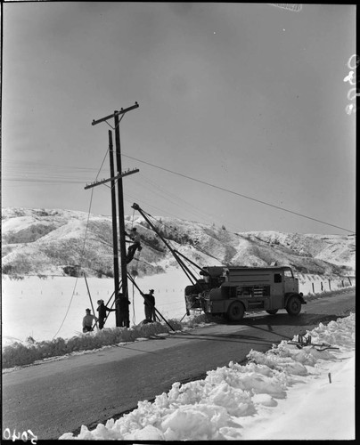 Linemen replacing a pole in the snow