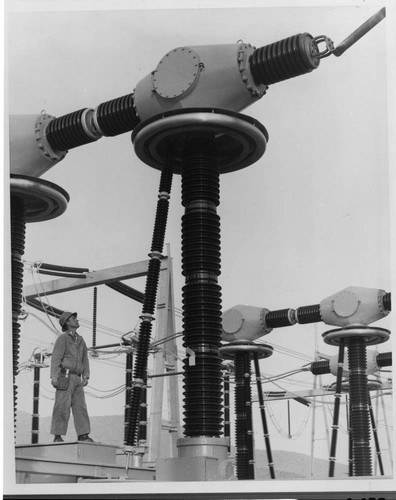 A substation maintenance man stands beside one of the new 500kV air circuit breakers at Vincent Substation