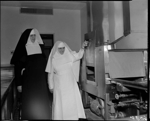 Two nuns looking at equipment in kitchen