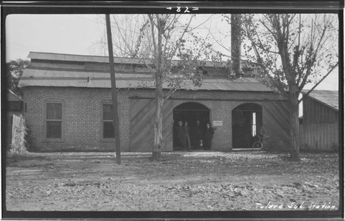 Exterior view of the Tulare substation with four operators standing in the doorway next to the "Danger; Keep Out" sign