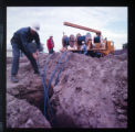 SCE linemen feeding underground conductors into trench at a construction site