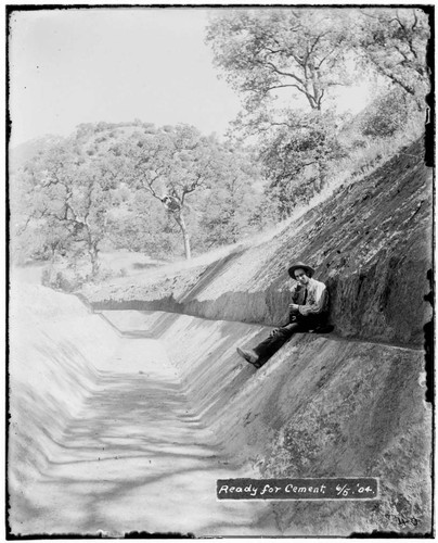 A man sitting in a ditch that is ready to be cemented at Kaweah #2 Hydro Plant