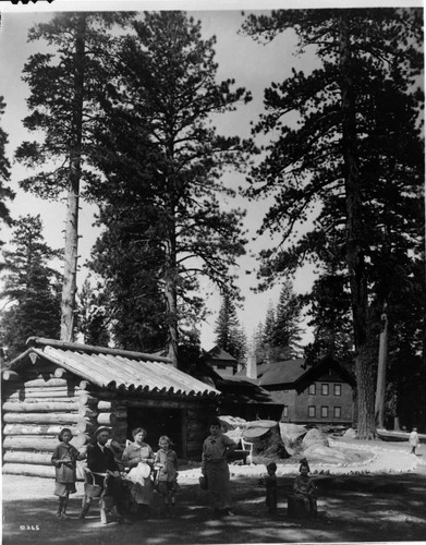 An unidentified family group sit in front of a rustic log structure known for many years as "Uncle Tom's Cabin."