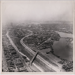 Aerial view, looking south from around 16th Avenue, of the Nimitz Freeway being constructed through the Jingletown and Kennedy Tract districts of Oakland, California. Montgomery Ward distribution center in view on the far left