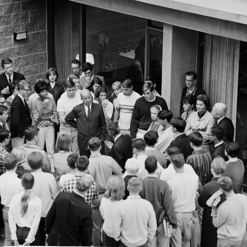 Clark Kerr, Edward Goldberg (back to camera), and John S. Galbraith (at right) in discussion within group of students and faculty during the installation of Galbraith as Chancellor, UC San Diego