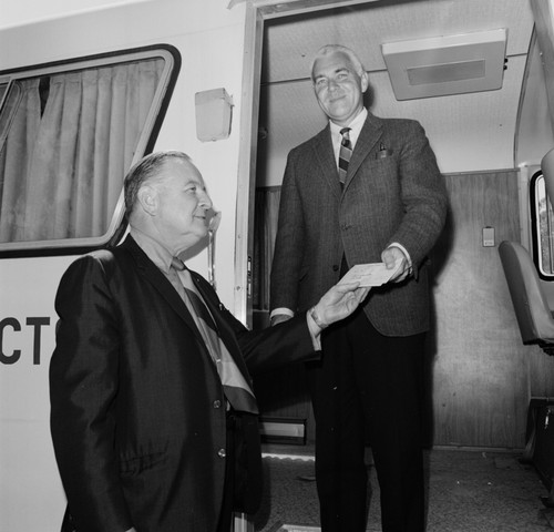 Chancellor William J. McGill (standing in mobile unit) receiving a donation check from Sears, Roebuck and Company representative