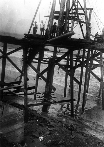 Construction workers emptying sand bucket (long tube) during the construction of the Scripps pier