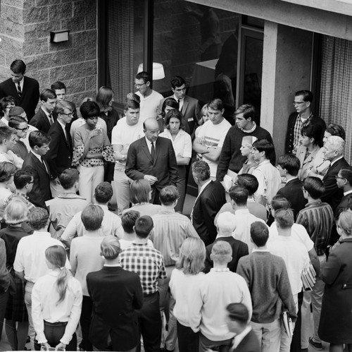 Clark Kerr, Edward Goldberg (back to camera), and John S. Galbraith (at right) in discussion within group of students and faculty during the installation of Galbraith as Chancellor, UC San Diego