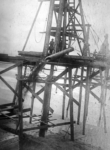 Construction workers emptying sand bucket (long tube) during the construction of the Scripps pier