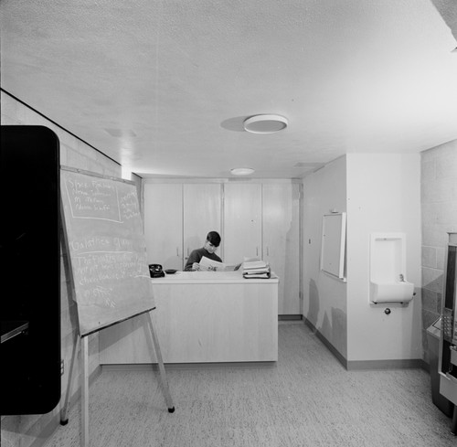 Man seated at reception desk, women's dormitory, UC San Diego