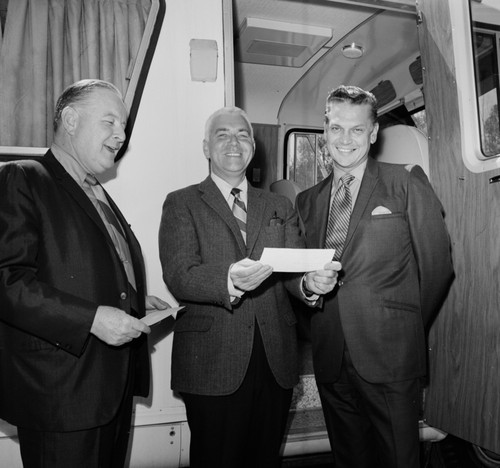 Sears Roebuck Company representatives awarding UC San Diego Chancellor William J. McGill (center) a check to pay for a new mobile unit (in background)