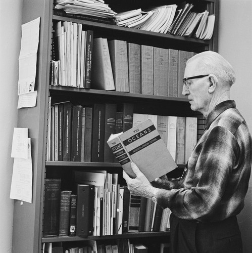 Martin W. Johnson holding his book, The Oceans