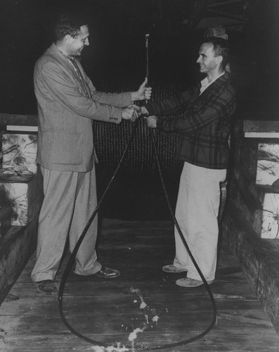 Roger Revelle holding wire cable and shaking hands with Jeffery D. Frautschy (right)