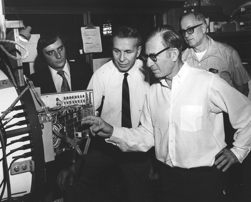 Walter Heinrich Munk (foreground) viewing deep-ocean internal waves recording system, with Michel J.M. Beguery (left), Jean-Pierre Levy, and Bernard Zetler (behind)
