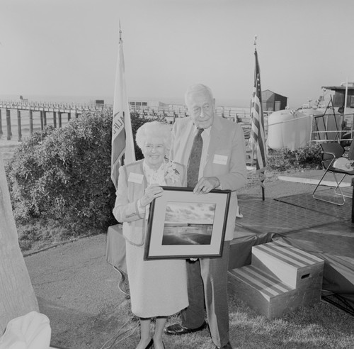 Ellen Virginia (Clark) Revelle and Roger Revelle holding photograph, Ellen Browning Scripps Memorial Pier rededication ceremony, Scripps Institution of Oceanography