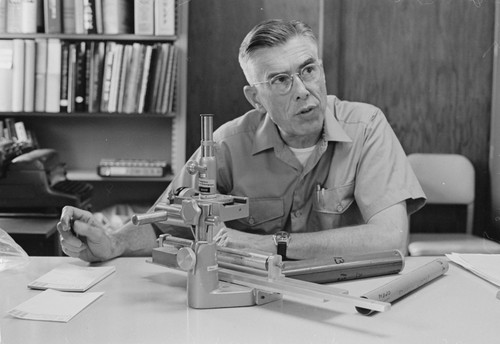 James M. Snodgrass at microscope, developing head set equipment for shark bites