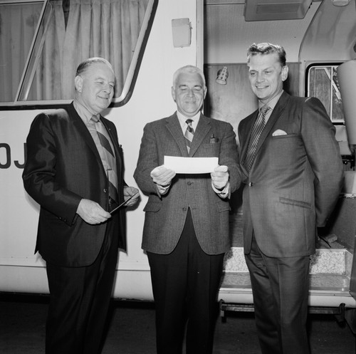 Sears Roebuck Company representatives awarding UC San Diego Chancellor William J. McGill (center) a check to pay for a new mobile unit (in background)