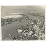 Aerial view of the Oakland estuary looking west, showing Sunset Lumber Company on High Street and Alameda shipyards